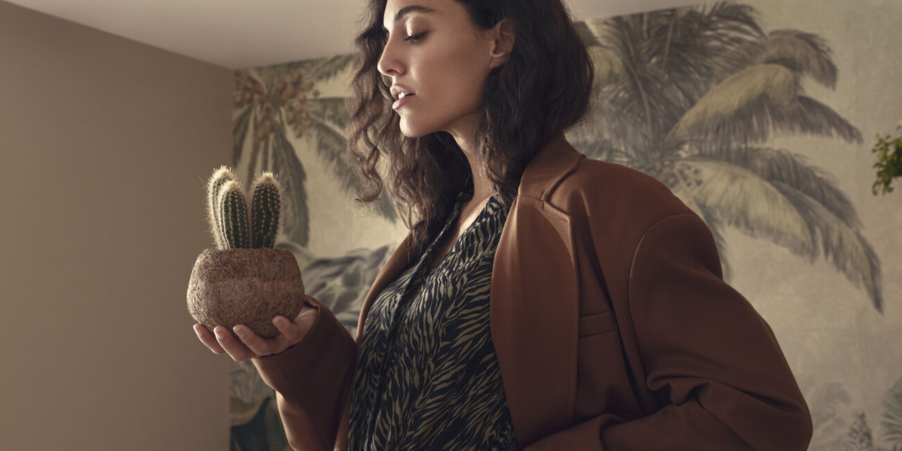 Editorial Photography | Serie Summernight | Studioaufnahme mit tropischen Pflanzen und Model auf dem Stuhl stehend mit Kaktus